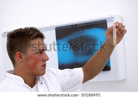 A young male lab technician looks at samples in a test tube.