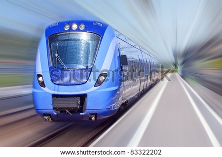 A passenger train travels at high speed through a train station with everything bar the train blurred out.
