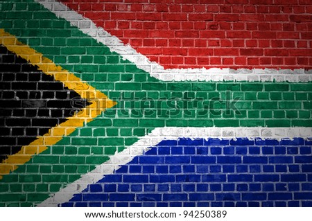 An image of the South Africa flag painted on a brick wall in an urban location