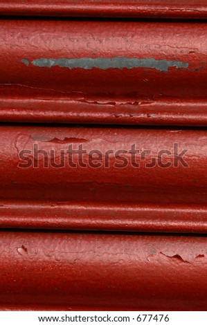 Peeling red roller security shutters on a shop front in North Wales.
