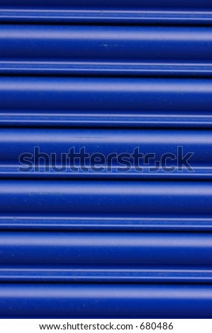 Glossy blue roller security shutters on a shop front in North Wales.