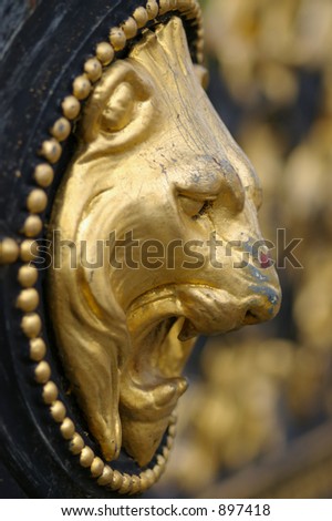 A side-on view of the decorative head of a golden lion on the gate-post of the Town Hall gates in Warrington, Cheshire, UK.