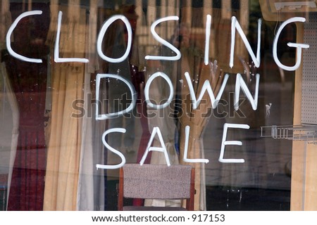 A Closing Down Sale sign painted on the window of a dress shop.
