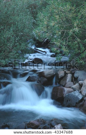A fast moving creek filmed with a slow shutter speed in early evening.