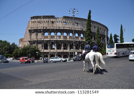 ROME, ITALY - JULY 10: Police patrol on horses crosses busy street in front of Colosseum on July 10, 2012 in the center of Rome, Italy. Experts say Colosseum has started to tilt and may need repairs.