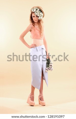 Fashion model posing in pastel clothes on beige background.