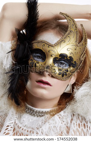 Beautiful young woman in gold mysterious venetian mask. Fashion photo