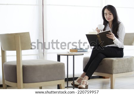 Attractive asian woman reading a book in the cafe.