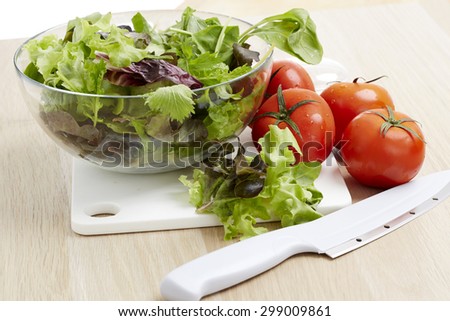 Fresh vegetables and salad ingredients on a wooden kitchen table.