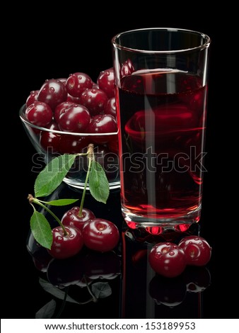 The glass vase of berries of a cherry and glass of cherry juice are isolated on a black background.