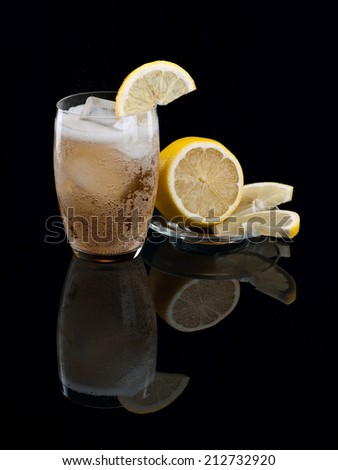 Lemonade with ice and a lemon on black