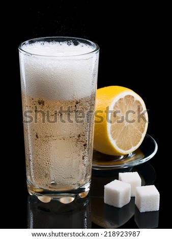 Lemonade with ice and a lemon on black