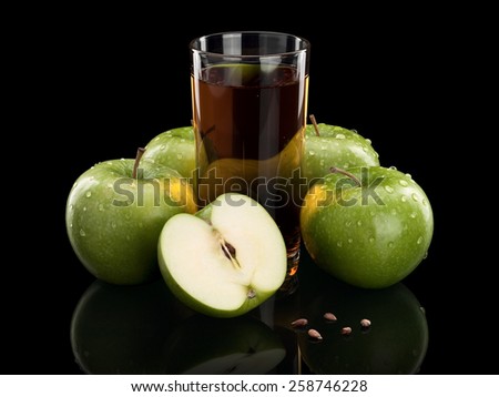 Four whole green apples, one part of an apple and juice glass