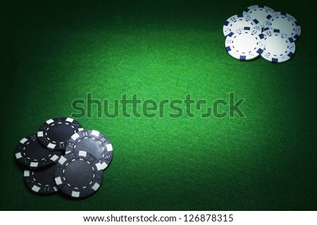Black poker chips versus White poker Chips on green casino felt with copy space between. Gambling concept