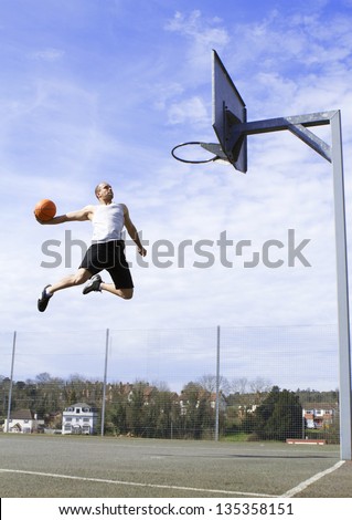 Basketball Player in mid air about to Slam Dunk