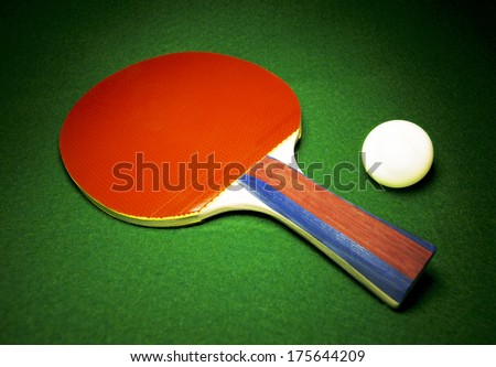 Table Tennis paddle and ball resting on green felt, nice concept of activity or competition