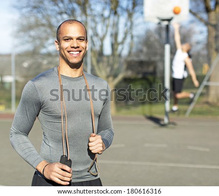 Portrait of a young healthy man holding a skipping jump rope and smiling to camera