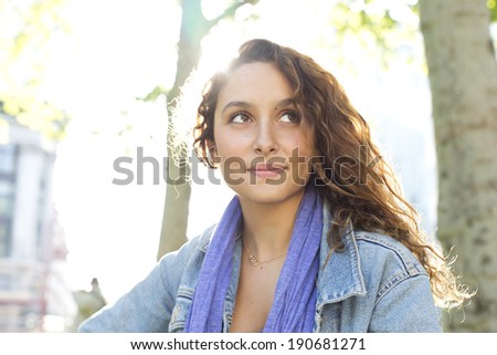 Portrait of an attractive young woman subtly smiling herself and looking off camera on a bright sunny day