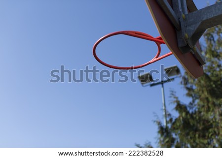 Basketball ring with no net on an outdoor basketball court in the sunlight