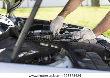 Mechanic hands installing new spark plugs in a car