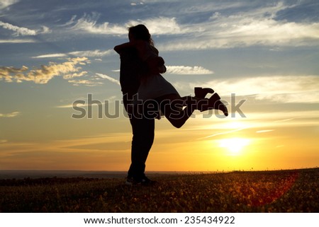 Happy silhouette couple embracing as the answer is yes to a marriage proposal against the background of sunset