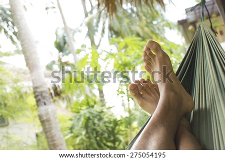 Feet resting in a hammock in a tropical environment