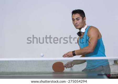 Handsome asian man about to return a shot during a game of table tennis, space for text or graphics