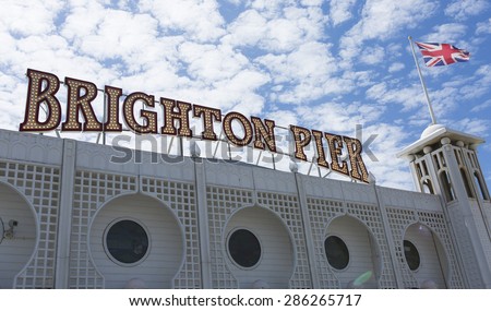 Brighton, UK - JUN 4, 2015 - Brighton Pier sign lit up on a sunny day with the UK flag flapping in a light breeze