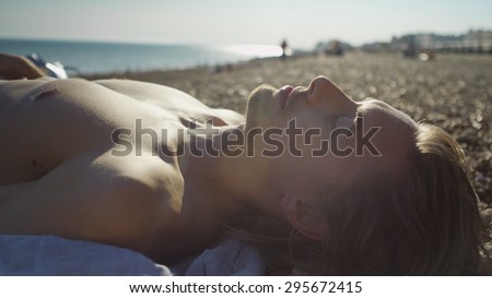 Handsome man lays topless on a beach on a hot day