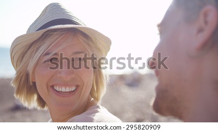 Attractive female glances and smiles at her charming boyfriend on the beach