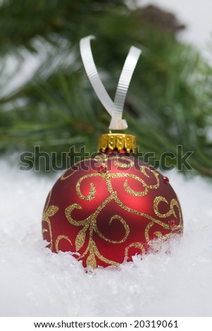 Red & gold glass Christmas ornament in a snowy setting
