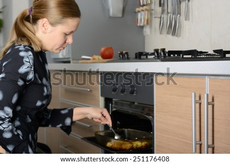 The woman in the kitchen preparing the potatoes in the oven