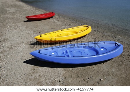 colorful kayaks on beach by turquoise waters