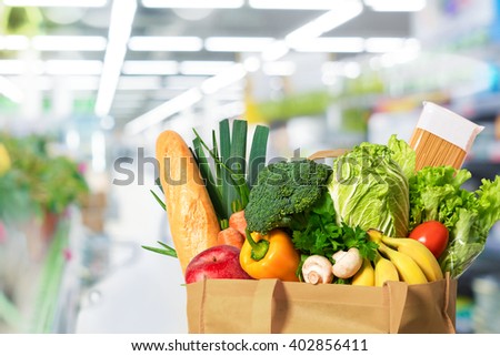 Eco friendly reusable shopping bag filled with vegetables on th supermarket background