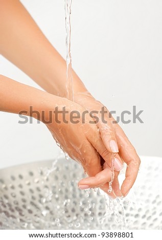 Water stream and splashing on woman\'s hands on white background under the sink