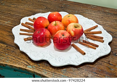 Seven Red apples on a white dish with cinnamon stick