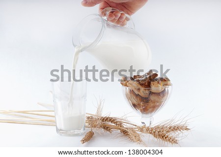 Man hand pouring milk from jug into the glass near with puff pastry in piala and spikelets.