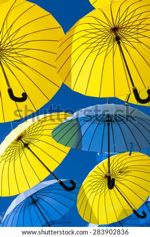 Yellow and blue umbrellas under a clear sky.