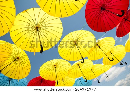 Yellow and blue, red umbrellas under a cloudy sky.