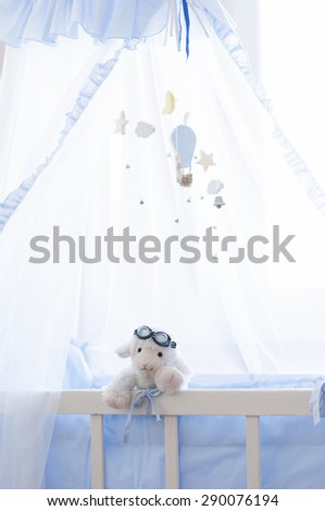 Baby cot with hanging wooden toys.