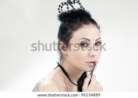 beautiful girl with a black crown on her head and put her lips to the key in the form of jewelery