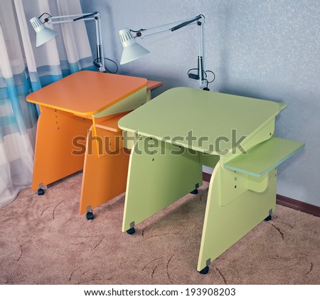 Two home desks: light green and orange in the corner of a room at the blue wall on a brown carpet