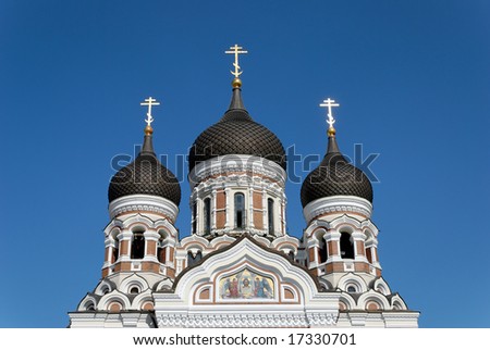 The upper part of St. Alexander Nevsky Cathedral in Tallinn, Estonia with golden crosses glowing in the evening sun.
