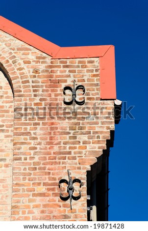 A corner of a brick house with two cast iron fixtures on polarised deep blue sky.