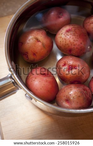 Fresh uncooked red new potatoes in a silver stainless steel pot.