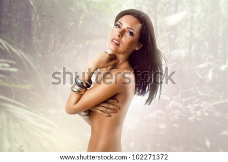 sexy nude girl posing with cheetah pattern makeup against rain forest background