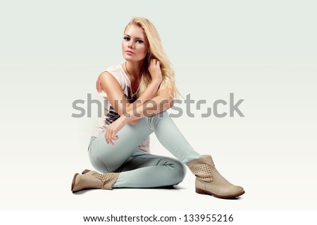 Beautiful Young Woman Wearing Casual Clothes And Boots Sitting On White Background