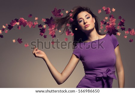 autumn portrait of beautiful woman wearing purple dress against maple leaves