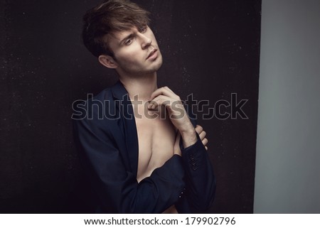 handsome young male model with naked torso in the studio dressed fashionably