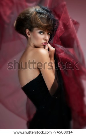 nice portrait of an attractive young girl with well done hair and delicate makeup black evening dress and covered with red material